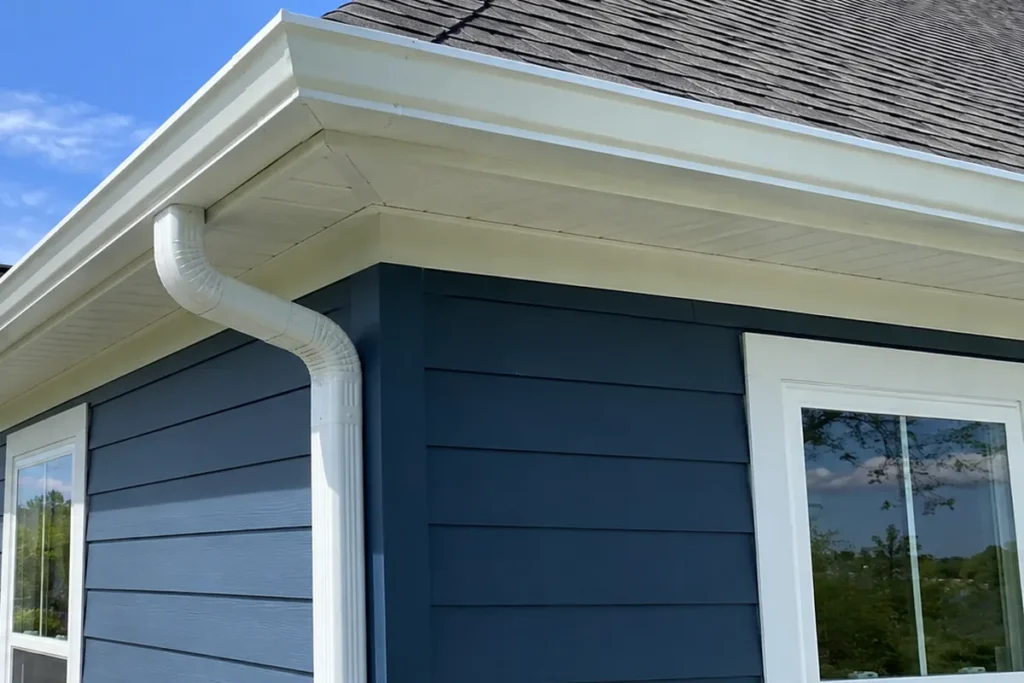 Close view of a white seamless gutter and downspout routing on a North Carolina home